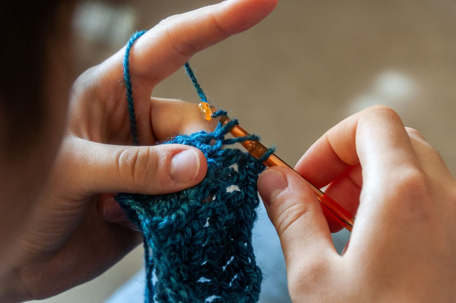 A crochet hook worked into a row of stitches in worsted weight yarn
