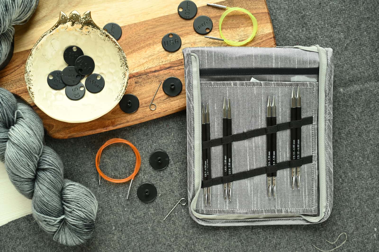 A beginner knitting kit laid out with needles, a yarn ball and a pattern card