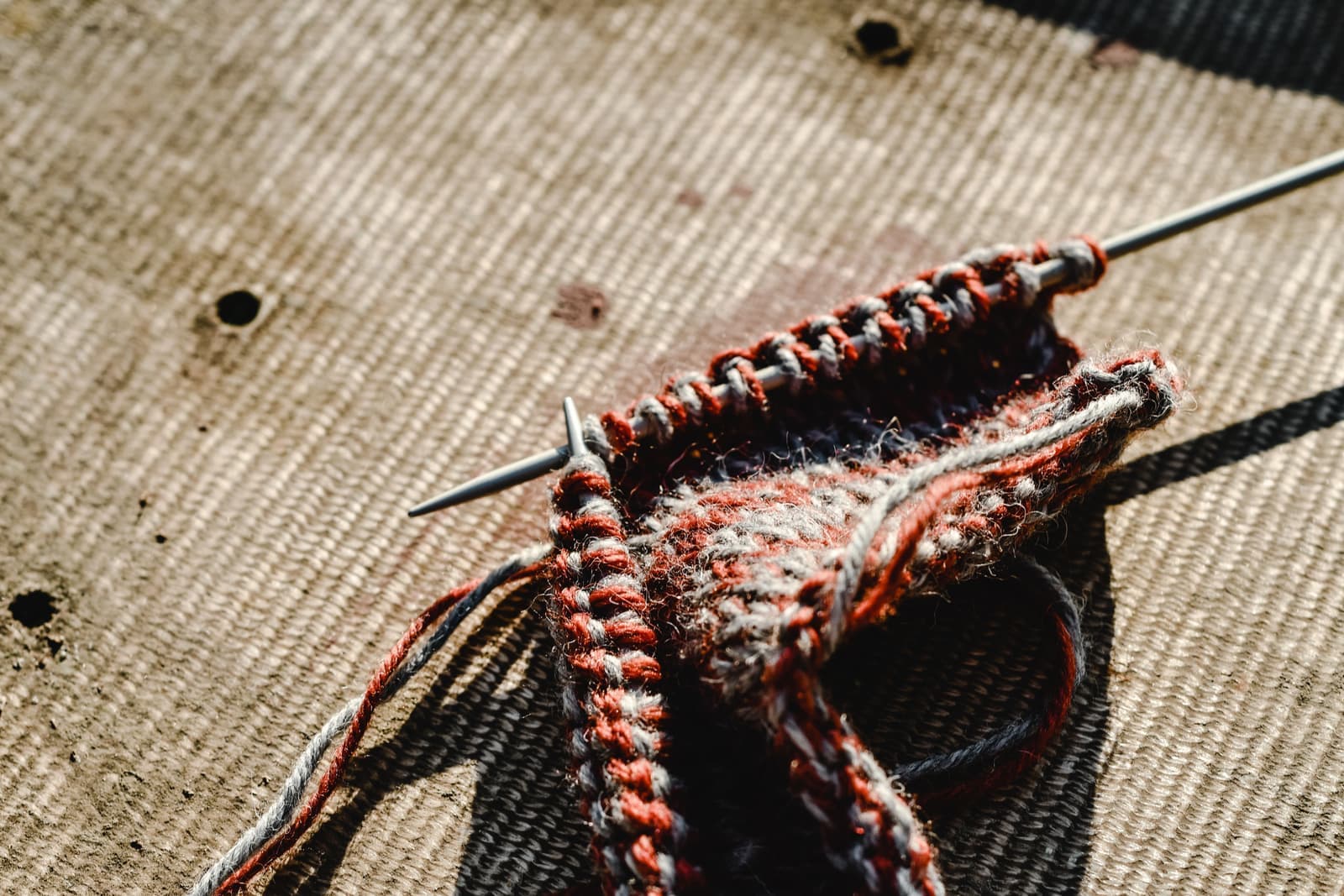 Circular knitting needles resting on a partly knitted swatch of wool yarn