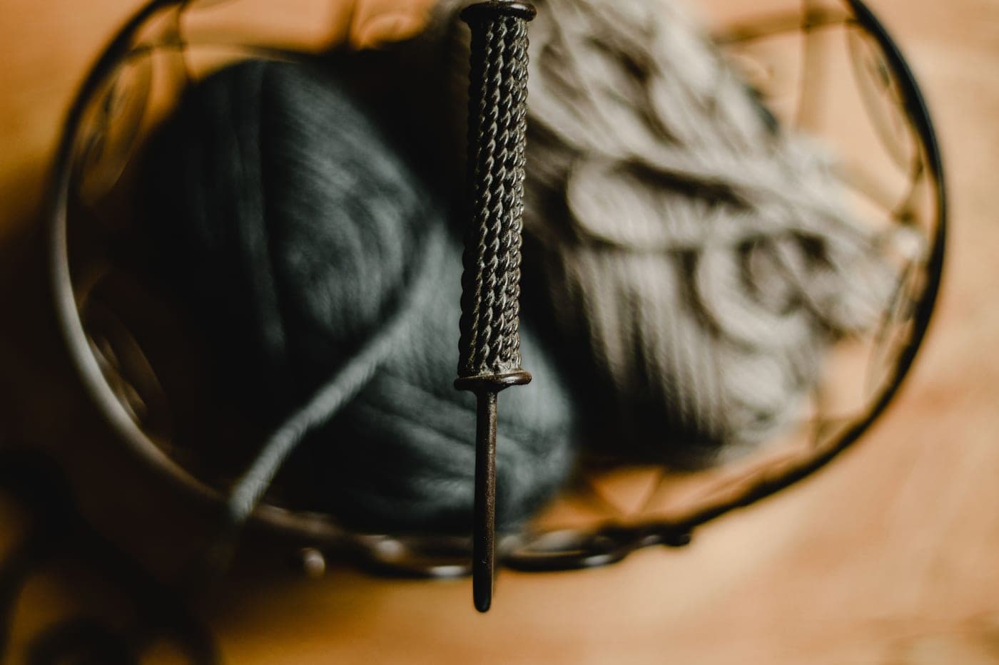 A partly knitted sweater body on circular needles beside skeins of wool yarn